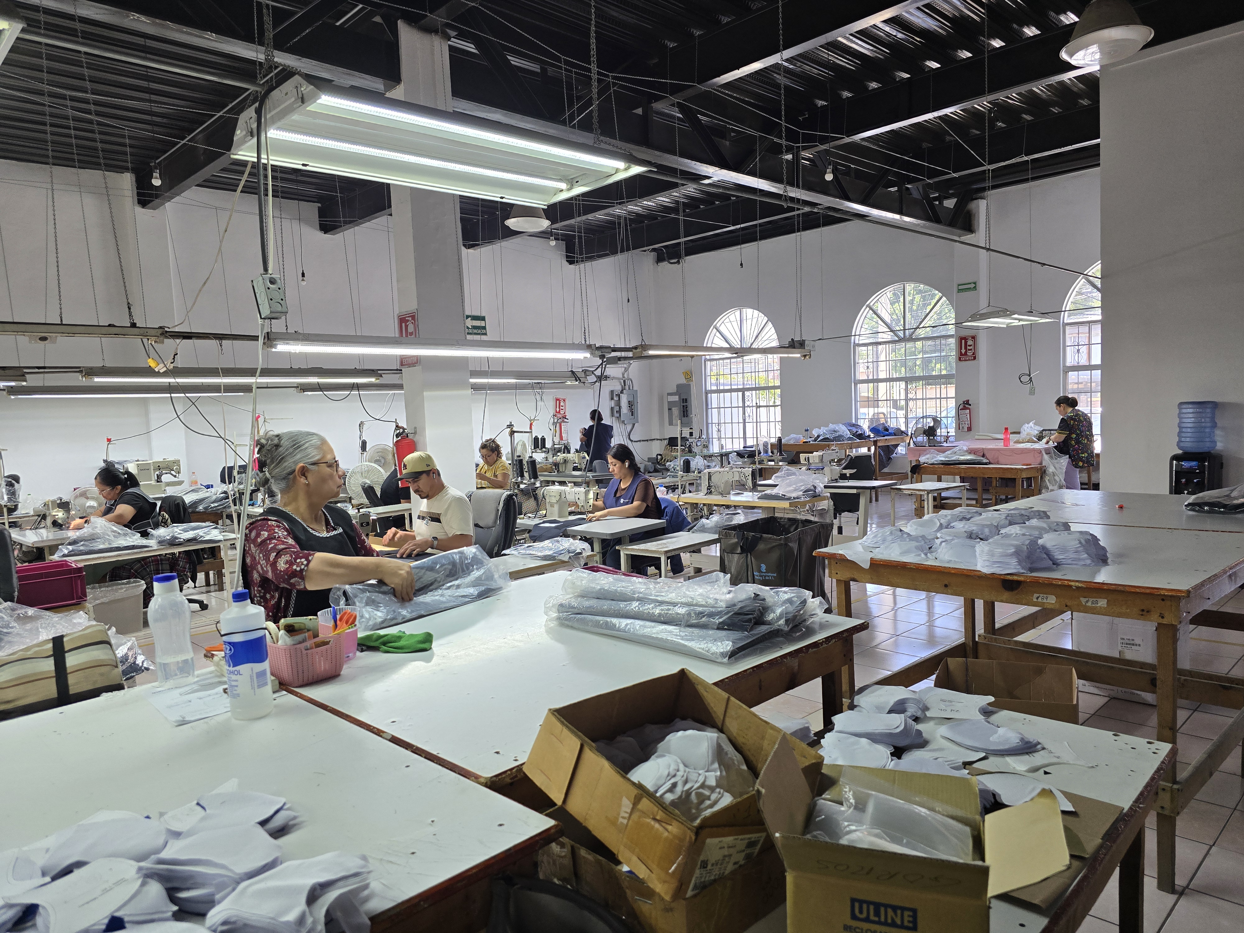 Sewing production floor in Tijuana — workers at industrial sewing machines assembling sewn products